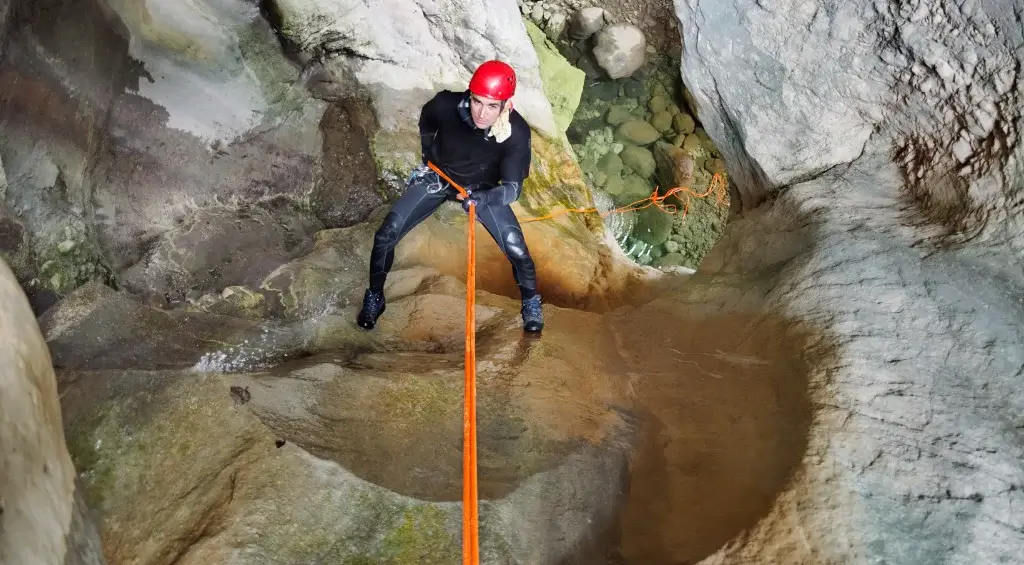 homem descendo caverna de rapel